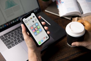 BANGKOK, THAILAND - 14 Nisan 2020: Kafeteryadaki ekranda sosyal medya simgeleriyle Iphone xr 'yi tutan kişi