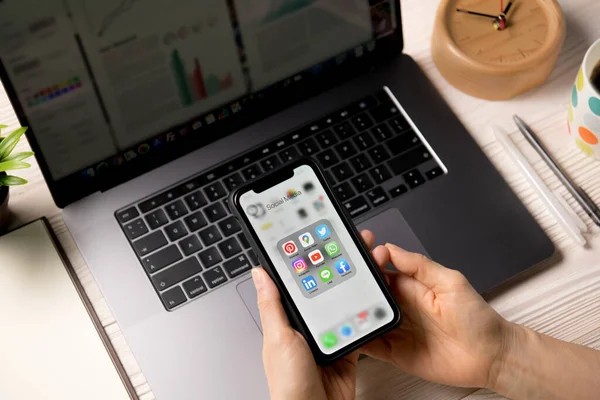 BANGKOK, THAILAND - 14 Nisan 2020: Ofisteki ekranda sosyal medya simgeleriyle Iphone xr 'yi tutan kişi
