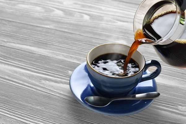 Ahşap Arka Planda Bir Fincanın Üzerine Dumanlı Kahve Dökmek — Stok fotoğraf