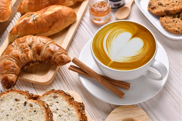 顶部的一杯咖啡拿铁面包或面包面包 羊角面包和面包店在白色木制桌子上 — 图库照片