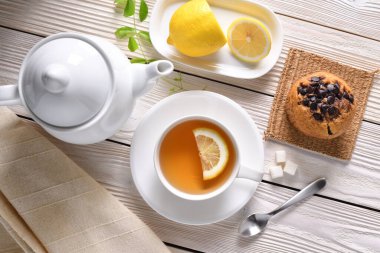 Limonlu bir fincan çay ve beyaz masada kek.