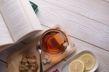 Tahta tepside çay fincanı. Kurabiye ve açık limon dilimleri. Rahat, rahatlatıcı ve huzurlu bir atmosferde.