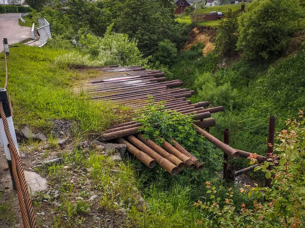 Colinas de rio altas com velhos tubos enferrujados e uma estrada . — Fotografia de Stock