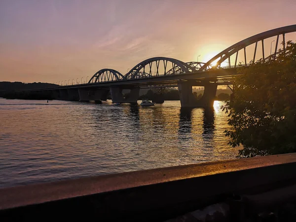 Pôr do sol atrás da ponte no rio Dnipro em Kiev, Ucrânia — Fotografia de Stock