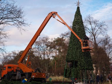 İşçiler parktaki Noel ağacını süslüyor.