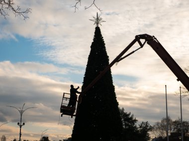 İşçi parktaki Noel ağacını süslüyor.