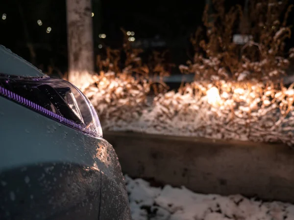 Powered on car headlights expose snowy roadside.