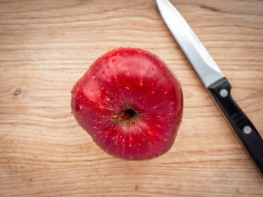 Tahta kesme tahtasının ortasında büyük kırmızı bir elma..