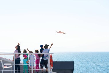 Kavala, Yunanistan - 21 Temmuz 2018: Yolcu gemisiyle adaya seyahat eden büyük bir aile ve martıları elleriyle besliyor.