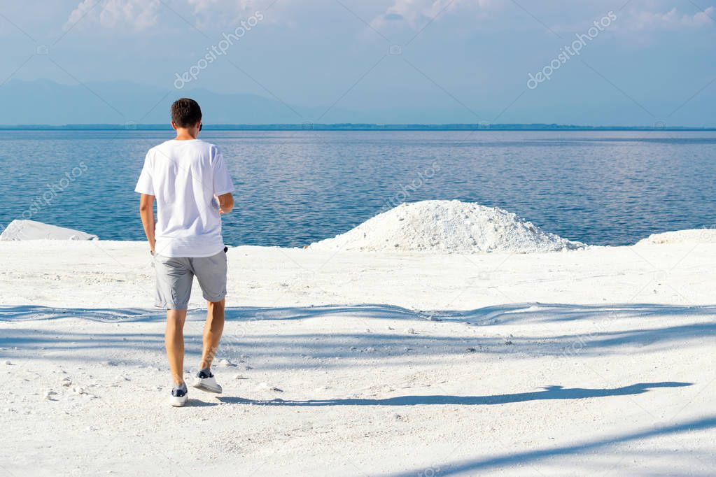Young man walking at Marble beach the famous place on island Thassos in Nothern Greece. The only snow white marble in Europe. Unique place concept