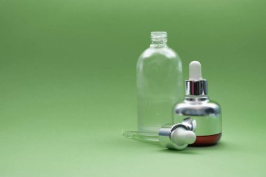 Yeşil arka planda cam pipetli lüks kozmetik şişesi ve mesaj için yer var. - Bakuchiol konsepti. Retinol alternatifi.