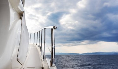 Fırtınalı hava şartlarında gün batımında beyaz lüks yat denize açılıyor. Yattan görünüm