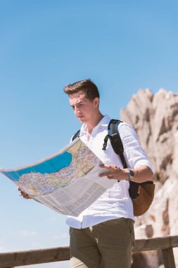 Kayaların arkasında duran elleri olan adam.