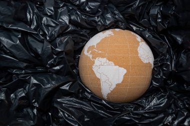 Siyah plastik torbalar arasında Dünya 'yı temsil eden mantar küre.