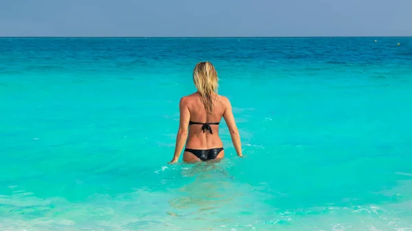 Woman in black bikini going in sea water
