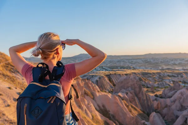 遠くに見えるバックパック付きの若い観光客の女性 日没時のカッパドキアの谷を観察 — ストック写真