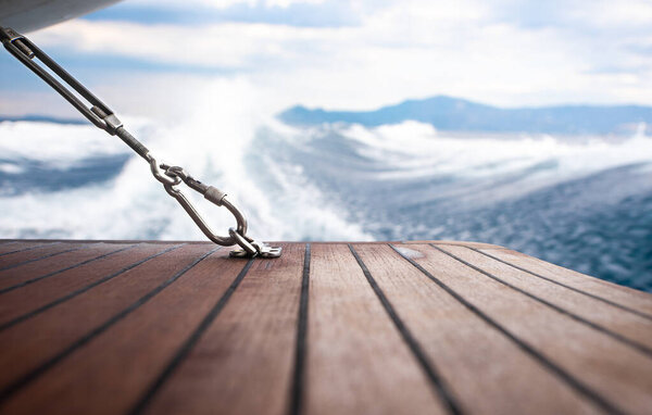 Close up stainless steel carabiner attached to wooden floor of yacht.
