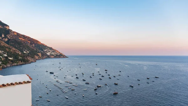 Yachts in the sea during sunset in front of Positano, Italy. High angle postcard view on gulf of Salerno.