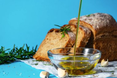 Zeytinyağı bir çay tabağına dökülüyor. Ekmek ve bitkilerle birlikte. Akdeniz mutfağı konsepti. Sağlıklı beslenme alışkanlıkları. Gmo özgür.