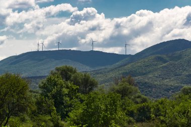Arka planda yel değirmenleri olan yeşil dağlar