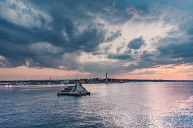 Arka planda deniz feneri ve Bari şehri olan liman, günbatımında bulutlu gökyüzü arka planda, İtalya.