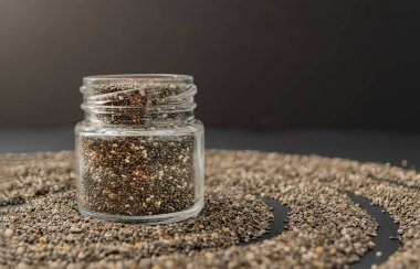 Siyah arka planda chia tohumları olan küçük bir kavanoz. Uzayı kopyala Chia süper yemek paleo diyet konsepti.