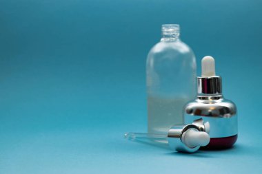 Mavi arka planda cam pipetli lüks kozmetik şişesi ve mesaj için yer var. - Bakuchiol konsepti. Retinol alternatifi.