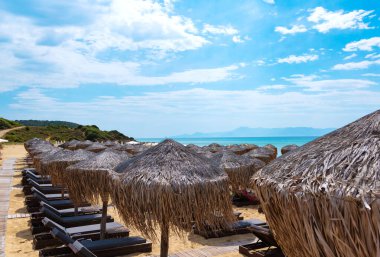 Konforlu şezlongları ve saman şemsiyeleri olan rahat plajlar. Konfor yaz tatili konsepti