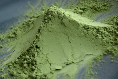 Close up pile of matcha powder on black plate. Natural matcha green tea concept. clipart
