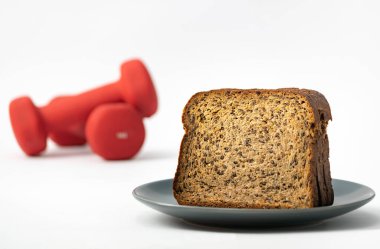 Fitness protein bread and unfocused red dumbbells on background. Helthy lifestyle sports concept. clipart
