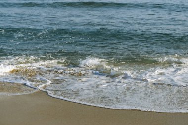 Deniz dalgaları kumlu kıyıya çarpıyor..