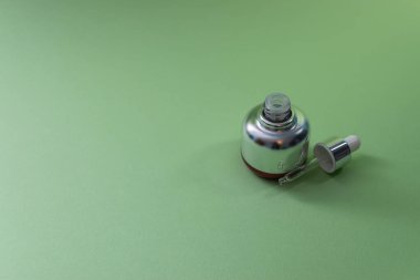 Yeşil arka planda cam pipetli lüks kozmetik şişesi ve mesaj için yer var. - Bakuchiol konsepti. Retinol alternatifi.