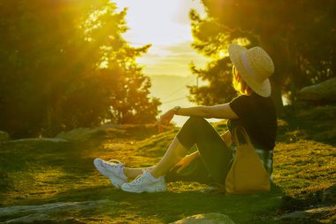 Sarışın kadın yeşil yaz ormanında dinleniyor.