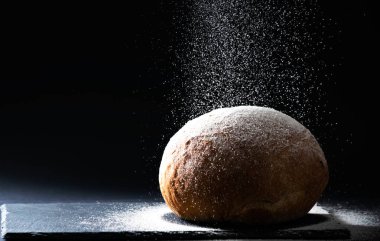 Ekmeği siyah arka planda düşen unla kapat. Ekmek yapma kavramı, kopyalama alanı, yatay.