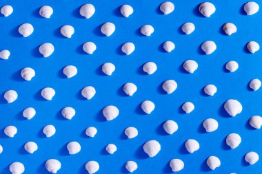 Mavi arka planda kusursuz bir şekilde beyaz deniz kabuklarının soyut düzlüğü. Yaz konsepti. Arkaplan dokusu. 