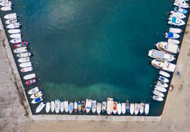 Limanın en üst manzarasında demirli tekneler ve yatlar var..