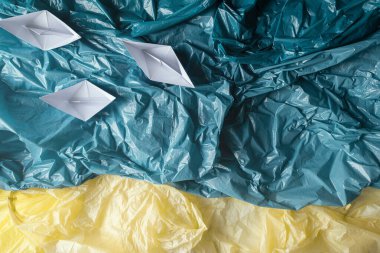 Plastikle okyanus kirliliği kavramı. Okyanus kıyısındaki plastik poşetlerden yapılmış kağıt teknelerin yukarıdan görünüşü. Plastik okyanusun, düz yatağın, kopyalama alanının yaratıcı temsili.