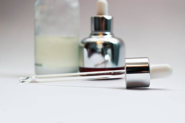Cam cilt pipeti ve arka plandaki odaklanmamış kozmetik şişelerine yakın çekim yapın. Bakuchiol konsepti. Lüks cilt ürünleri konsepti.