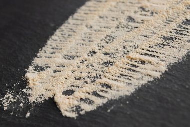 Kara taş yüzeyindeki maca tozunu kapatın. Süper gıda malzemeleri konsepti.