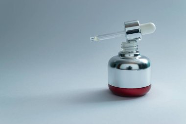 Beyaz arka planda cam pipet ve fotokopi alanı olan pahalı bir cilt bakımı şişesi. Retinol alternatif konsept. Bakuchi tohumları özü.