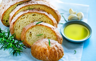 Rosmarine 'li ekmek dilimleri ve mavi arka planda papirin üzerine zeytinyağlı çay tabağı. Glütensiz sağlıklı yeme konsepti. Akdeniz mutfağı.
