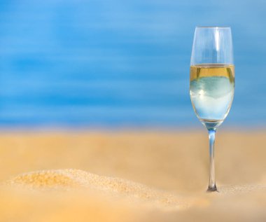 Mavi denize karşı kumlu sahilde şampanya kadehleri. Yaz konseptini kutlayalım. Seçici odak, bulanık arkaplan, metin için boşluk
