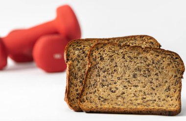 Fitness protein ekmeği ve arka planda odaklanmamış kırmızı dambıllar. Helthy yaşam tarzı spor konsepti.