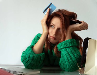 Bilgisayarı ve kredi kartıyla online alışveriş yapan bir kadın.