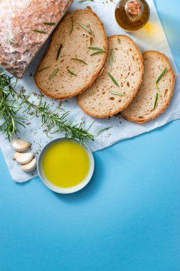 Slices of bread on papyrine with garlic, olive oil and rosmarine. Vertical, flat lay, copy space. Gluten free healthy eating concept, mediterranean cuisine. clipart
