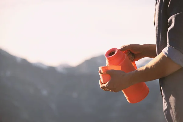 山の中のカップに魔法瓶からお茶を注ぐ男の近くのビュー — ストック写真