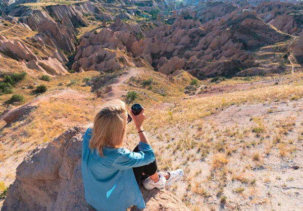 Woman with tumbler cup of coffee sitting on the hill enjoying scenery.
