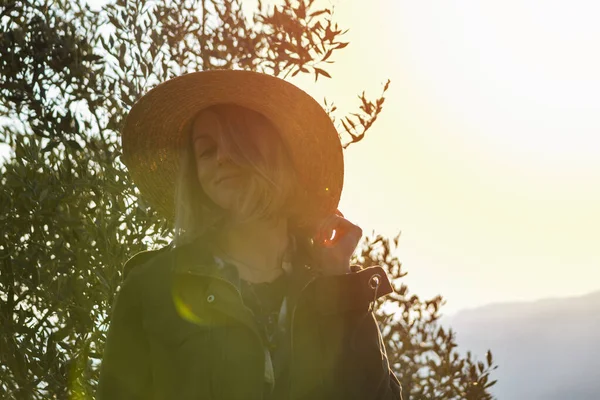 年轻的女人戴着草帽对着相机笑. 夕阳西下 欢乐时光旅行的概念. — 图库照片