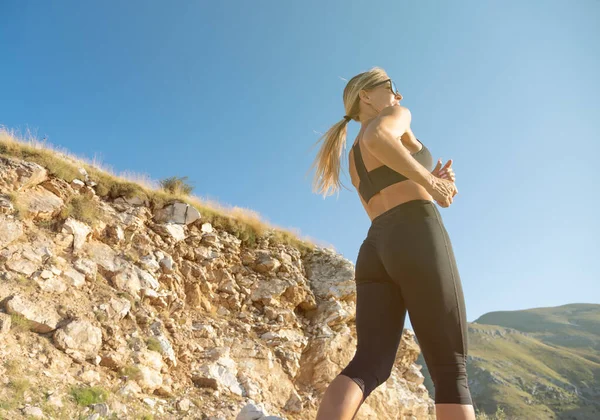 Young blonde woman jogging in mountains