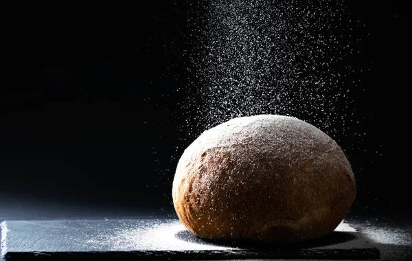 Ekmeği siyah arka planda düşen unla kapat. Ekmek yapma kavramı, kopyalama alanı, yatay.